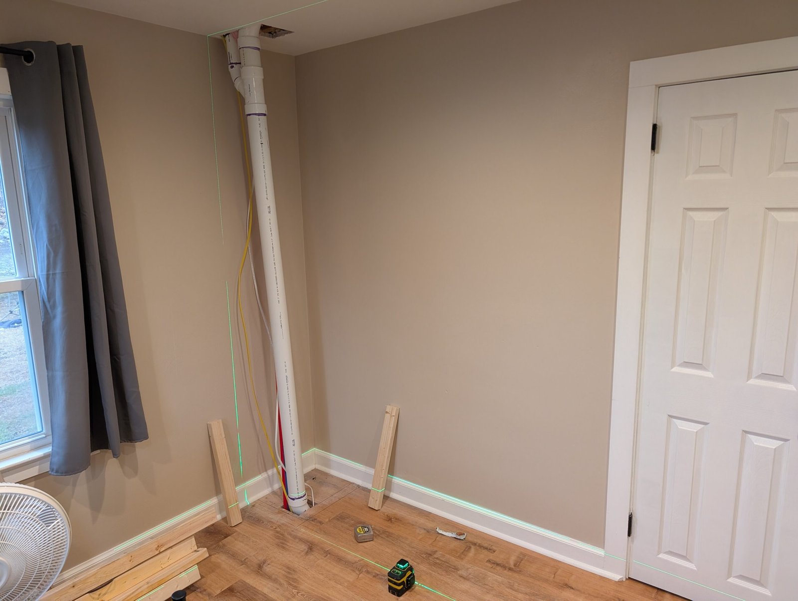 Laser line marking the closet layout on the wall, showing the precise planning for enclosing the plumbing