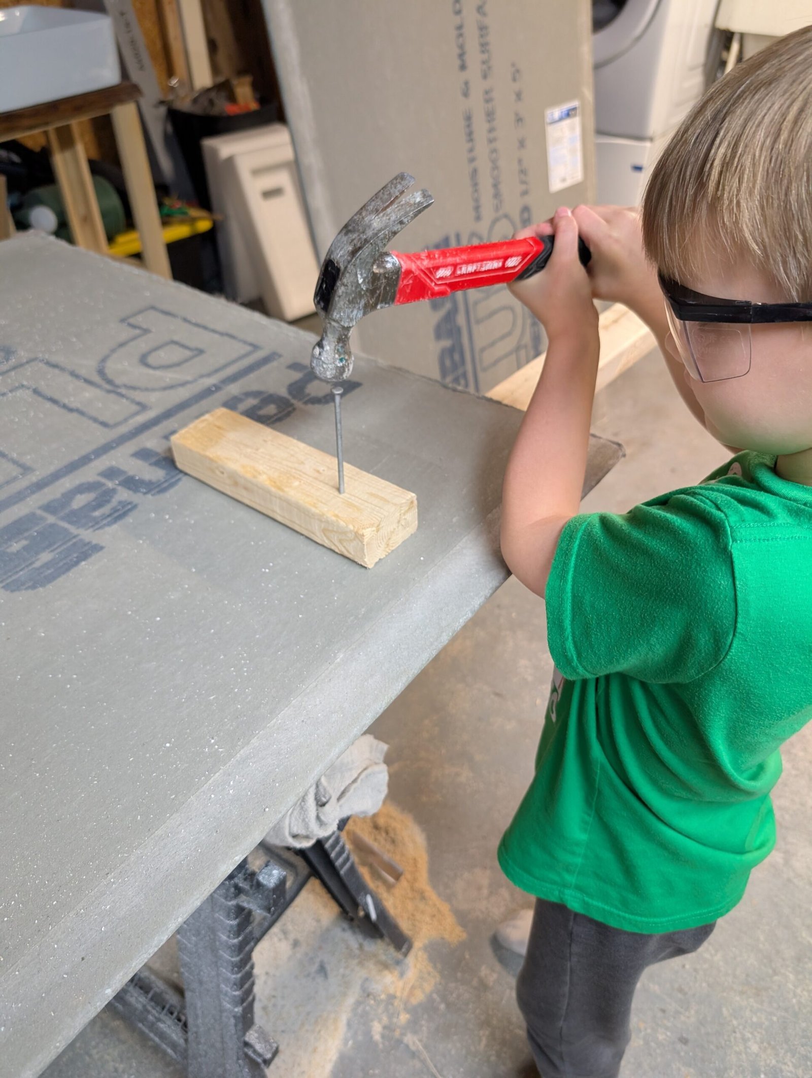 Kid-Safe DIY: Teaching My 8-Year-Old to Hammer (With Zero Drama) Wyatt hammering a nail with safety glasses on, focused and ready